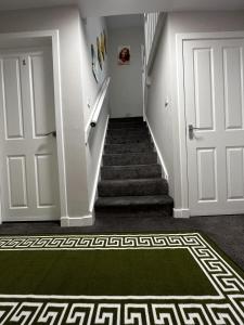pasillo con escalera y alfombra verde en Hesed Home en Edimburgo