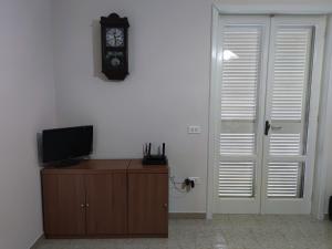 Zimmer mit einem TV und einer Uhr an der Wand in der Unterkunft Villa Carmine & Gina in Castel Volturno