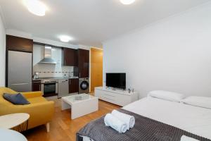 1 dormitorio con cama blanca y sofá amarillo en Estilo en calle Brasil by CABANA Rentals, en Vigo