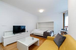 Sala de estar blanca con sofá amarillo y cama en Estilo en calle Brasil by CABANA Rentals, en Vigo