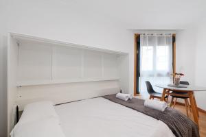 Dormitorio blanco con cama y mesa en Estilo en calle Brasil by CABANA Rentals, en Vigo