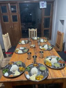 una mesa de madera con platos de comida. en Pasne Aajako Hotel, en Bandipur