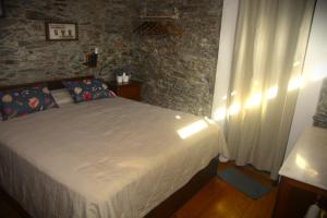 ein Schlafzimmer mit einem Bett und einer Steinmauer in der Unterkunft Casa do Valo in Amonde