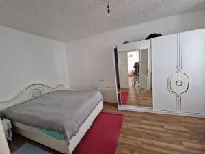 a white bedroom with a bed and a mirror at Modern und Gemütlich in Ebenfurth