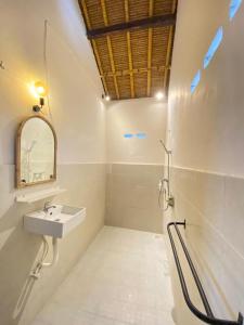 ein Bad mit einem Waschbecken und einem Spiegel in der Unterkunft Surf Shack Grupuk in Bumbang