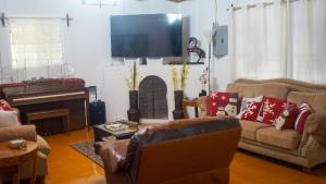 un soggiorno con divani, TV e pianoforte di Neysa's Vacation House a Los Naranjos