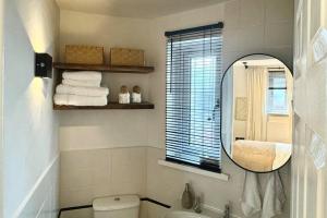 uma casa de banho com um espelho, um WC e uma janela em No.1 Lighthouse Dawlish Beach em Dawlish