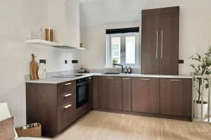 a large kitchen with wooden cabinets and a window at No.1 Lighthouse Dawlish Beach in Dawlish