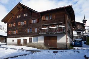 een groot houten huis met een balkon in de sneeuw bij Cosy traditional mountain house in scenic valley in Cumbels