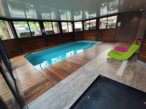 - une piscine avec une chaise verte dans un bâtiment dans l'établissement Domaine du Clos Fleuri - Spa, à Honfleur