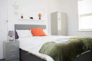 a bedroom with a large white bed with an orange pillow at Charming 4BR House in Liverpool FC in Liverpool
