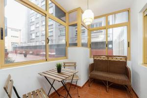 a room with a table and a chair and windows at Con parking gratis en el centro by CABANA Rentals in Vigo
