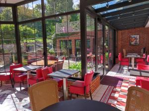 un restaurante con sillas rojas, mesas y ventanas en Domaine du Clos Fleuri - Spa, en Honfleur
