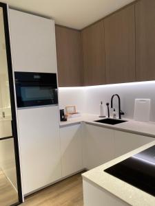 een keuken met witte kasten en een wastafel bij Luxe appartement `t Sant Nieuwpoort Bad in Nieuwpoort