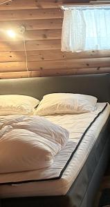Bett mit weißer Bettwäsche und Kissen in einem Zimmer in der Unterkunft Bäckstugan in Sälen