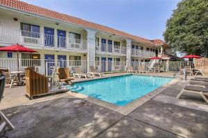 una piscina frente a un hotel con sillas y sombrillas en Motel 6-Pinole, CA, en Pinole