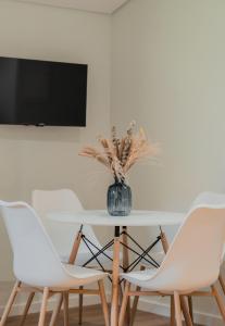 una mesa con dos sillas blancas y un jarrón con flores en Primeiro Quartel Apartments - 4, en Peso da Régua