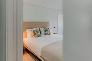 1 dormitorio con 1 cama con sábanas y almohadas blancas en Primeiro Quartel Apartments - 4, en Peso da Régua