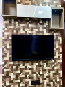 a flat screen tv hanging on a tiled wall at Homestay-a better living in Lucknow