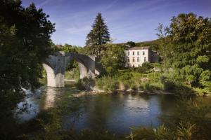 eine Brücke über einen Fluss mit einem Gebäude im Hintergrund in der Unterkunft La Maison du Pont Vieux in Cazilhac