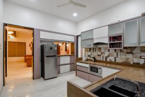 a kitchen with white cabinets and a stainless steel refrigerator at Villan Villa Luxurious Mountain View Biggest Pool in Lonavala
