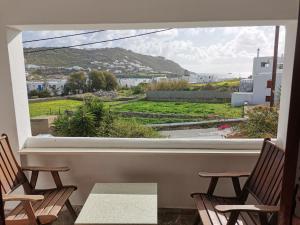 una camera con due sedie e una finestra con vista di VILLA VASILIS ORNOS a Mykonos Città