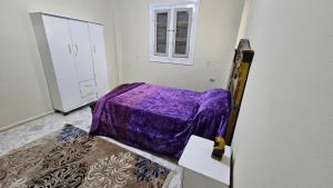 Private Room in Huge ApartmentQ في القاهرة: غرفة نوم بسرير ارجواني ونافذة