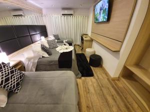 Habitación con cama, sofá y TV. en Lages Plaza Hotel, en Lages