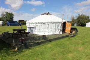 a yurt with a picnic table on a wooden deck at Glamping West Midlands in Enville