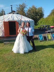 Una novia y un novio posando para una foto delante de una yurta en Glamping West Midlands en Enville