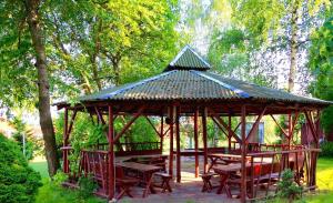 a wooden gazebo with a table and benches at Hotel i Restauracja Sara in Polanica-Zdrój
