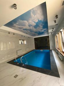 einen Pool in einem Zimmer mit einem Himmelsmalde an der Wand in der Unterkunft Ali假日民宿 in Almaty