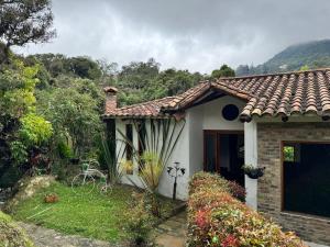 a small white house with a mountain in the background at Termales azules La Calera in El Salitre