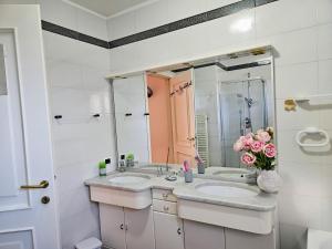 een badkamer met 2 wastafels en een vaas met roze rozen bij IL PEPE ROSA di Anna e Silvano in Sarzana