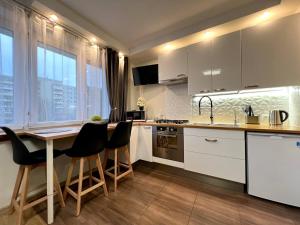 a kitchen with white cabinets and a table and chairs at K22 Airport Chopin Apart B in Warsaw