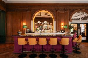 um bar com bancos de bar amarelos num quarto em The Bailey's Hotel London Kensington em Londres