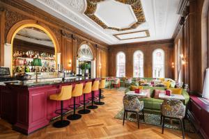 um restaurante com um bar com bancos de bar amarelos em The Bailey's Hotel London Kensington em Londres