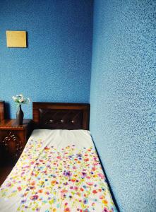 1 cama en un dormitorio con una pared azul en Grandmother Naziko, en Vani