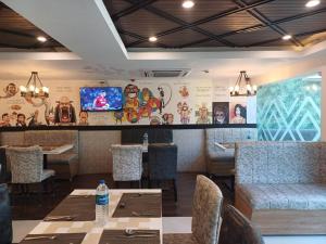 ein Restaurant mit einem Tisch und Stühlen sowie einem TV in der Unterkunft Hotel Marina Inn Egmore Chennai in Chennai