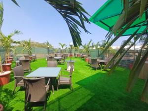 a patio with tables and chairs on grass at Hotel Marina Inn Egmore Chennai in Chennai