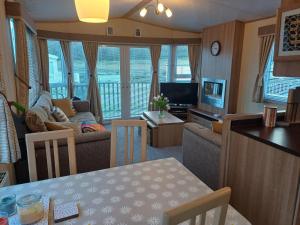 een woonkamer met een bank, een tafel en een televisie bij The Highlander in Tain