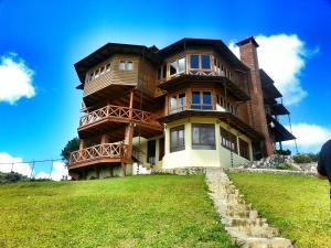 a large wooden house on top of a green field at Villas Las Neblinas in Constanza