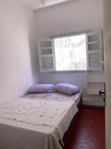 a small bedroom with a bed with a window at Pousada Tropical in Marataizes