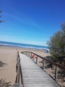 a wooden boardwalk leading to a beach with people at LAS TONINAS - CASAS DE PLAYA - a 50 metros del mar in Monte Hermoso