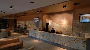 a lobby with a bar with people sitting at it at Plaza Hotel & Boulevard Convention - Vale dos Vinhedos in Garibaldi