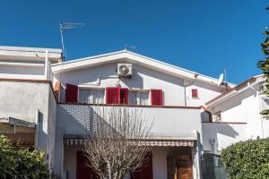 una casa bianca con persiane rosse e balcone di Comodo bilocale a Marcelli - M271 a Marcelli