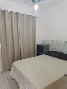 1 dormitorio con cama blanca y cortinas en Temporada Praia de Setiba en Guarapari