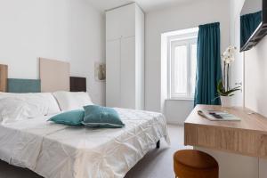 una camera da letto bianca con un letto e una scrivania di Nimar Suite a Formia