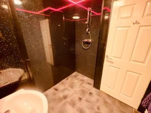 a bathroom with a toilet and a shower with pink lights at Winter Gardens Large Flat 1 in Blackpool