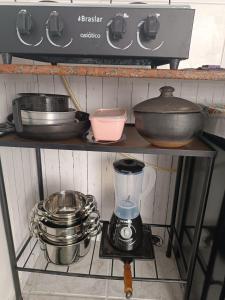 a kitchen shelf with pots and pans and a blender at Temporada Praia de Setiba in Guarapari